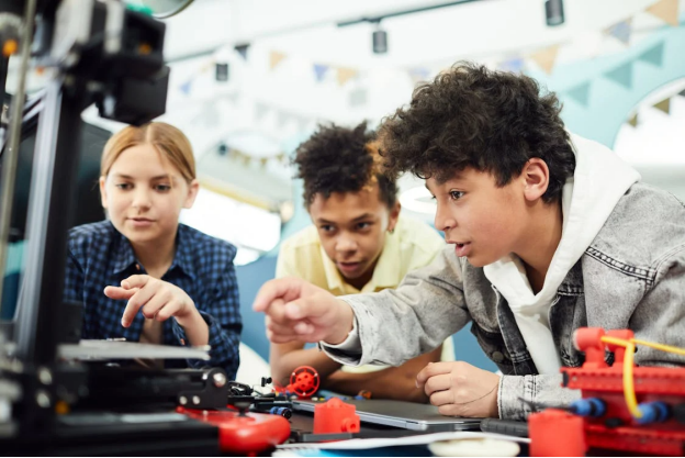 Three students working together on a hands-on project in a lab, demonstrating teamwork and integrity