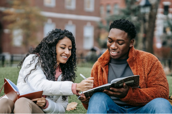 Young man and woman reviewing college budget notes in a notebook