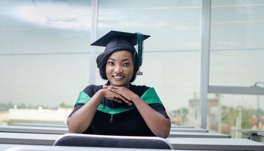 Woman in academic regalia smiling at graduation after receiving scholarship tuition support