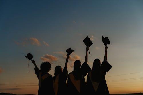 Group of diverse college students celebrating graduation in caps and gowns